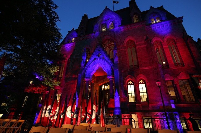 College Hall illuminated at night with royal colors